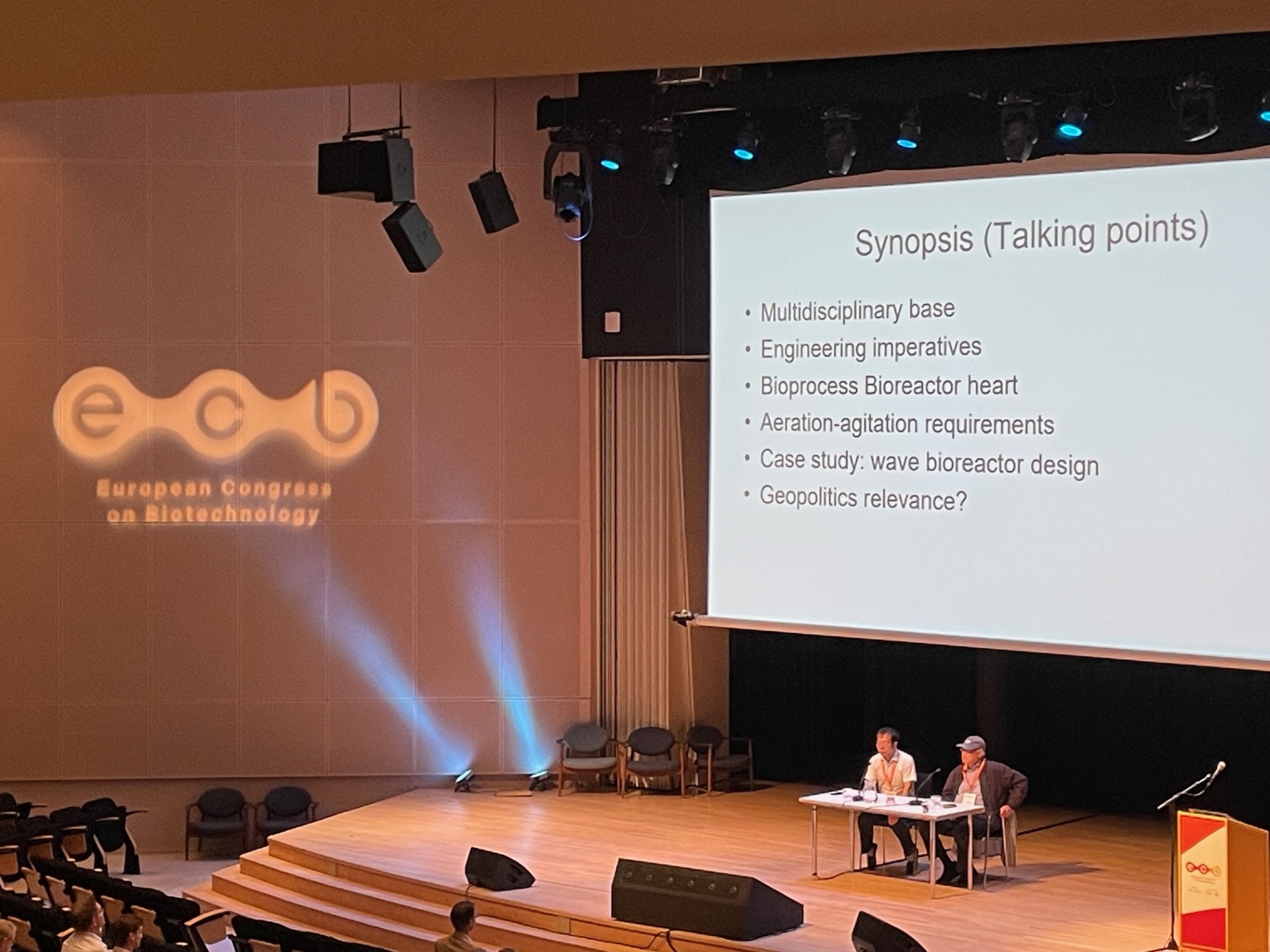 Panel discussion on stage with presentation slide at European Congress on Biotechnology
