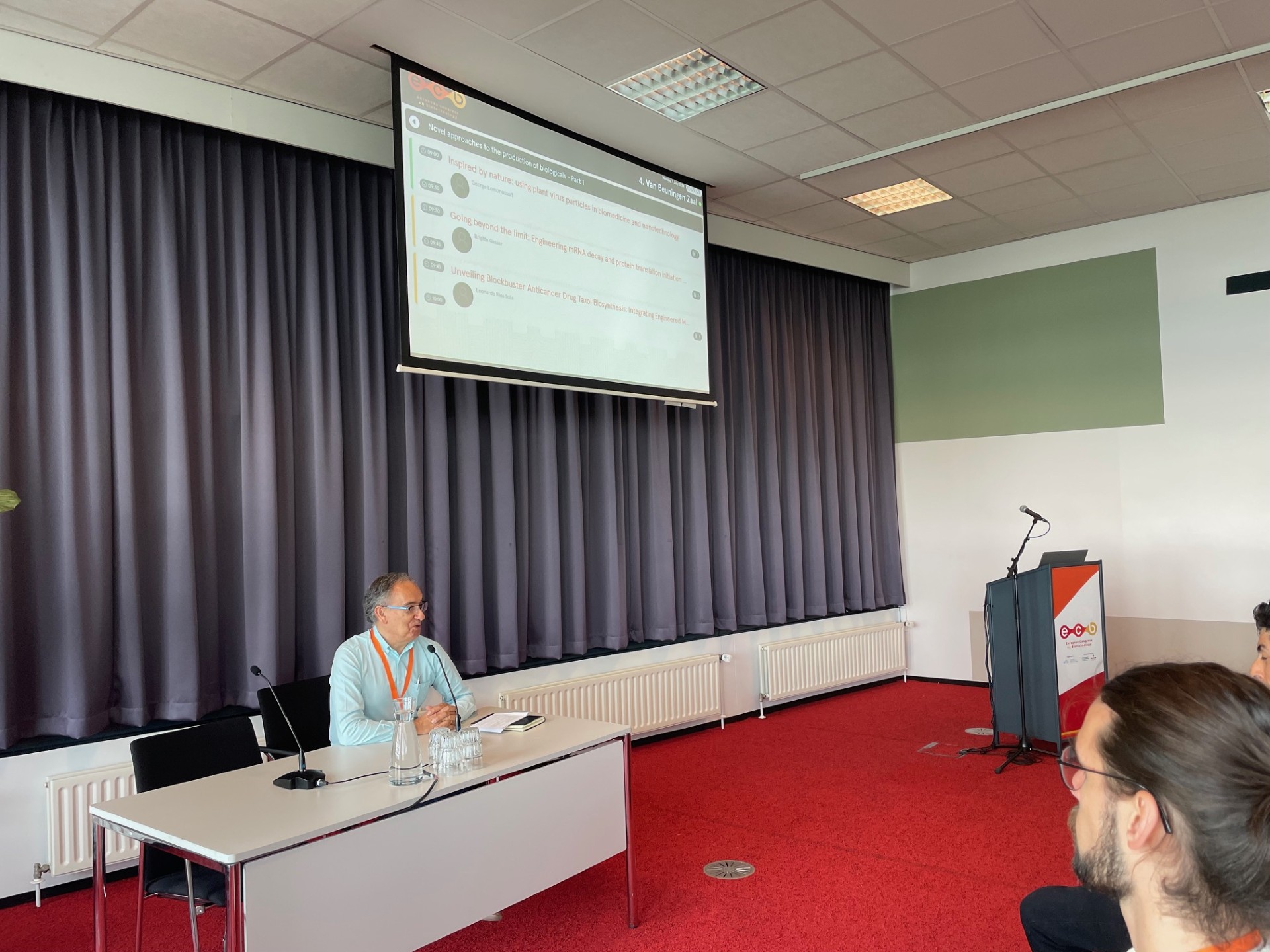 Francesc Godia presenting session in smaller room at European Congress on Biotechnology with projected program screen